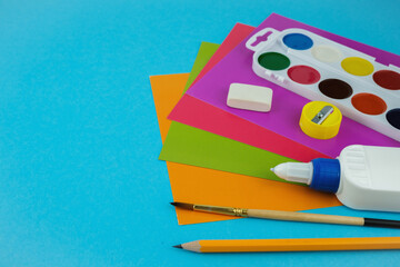 Flat lay stationery set , top view of  colourful paper, pencils, glue, ruler on blue background