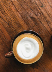 Top view of hot cappuccino with milk foam on wood table in coffee shop