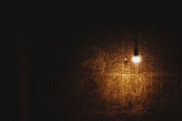 Lit bulb lightning up a brown stone wall