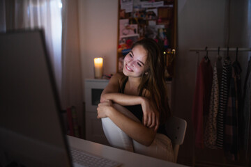 Happy young girl with computer at night smiling, online dating concept.