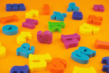 Naklejka premium Plastic colourful alphabet letters on the orange background.