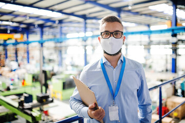 Fototapeta na wymiar Technician or engineer with protective mask working in industrial factory, standing.