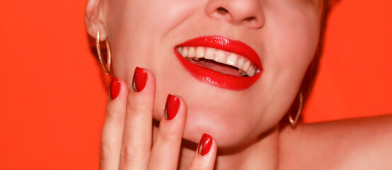 Lips with red lipstick and red manicure on an orange background. Classic lipstick color. Byuti background.