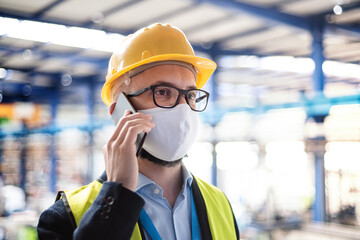 Fototapeta na wymiar Technician or engineer with protective mask and telephone in industrial factory.