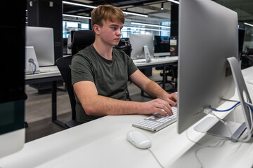 The concept of education, a young man sits at a computer, teaches students in the workshop, using a computer in high school, at the university, to study network communications and computer technology
