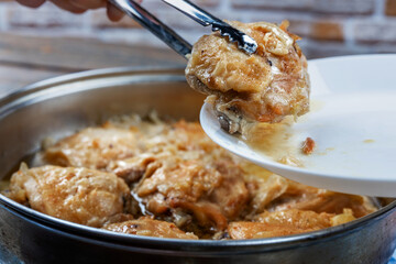 Chicken thighs are fried in a pan and served with spitz on a plate, close-up, shallow depth of field, selective focus. Homemade food concept.