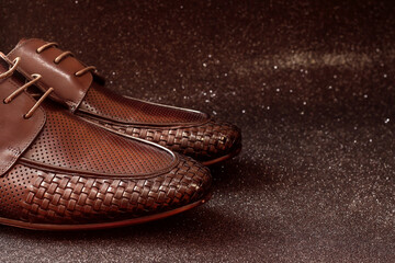 Brown men's shoes on a black background. Shoes with a weave.