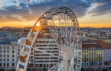 Budapest, Hungary - Aerial view of the famous ferris wheel of Budapest with Buda Castle Royal Palace and an amazing golden sunset and sky. The wheel is totally empty due to the Coronavirus disease