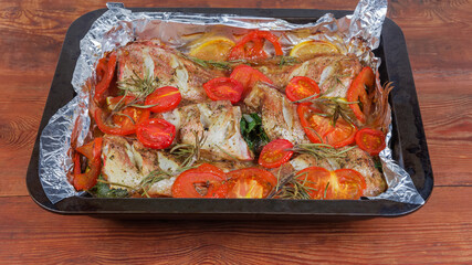 Baked ocean perch with tomatoes on the oven tray closeup