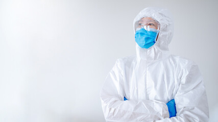 Doctor or physician in personal protective equipment standing with arms crossed posing in hospital clinic. Medical worker wearing PPE suit, mask and goggles for preventing Coronavirus (COVID-19).