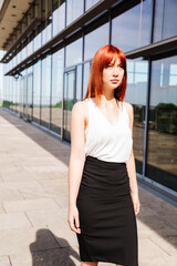 Fototapeta premium Young business woman walks along modern building