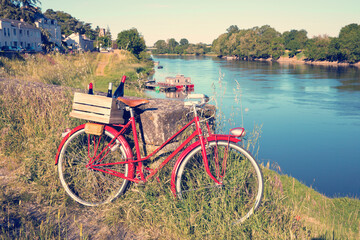 Vieux vélo rouge sur les bord de la Loire en France, caisse de vin rouge sur le porte bagage.