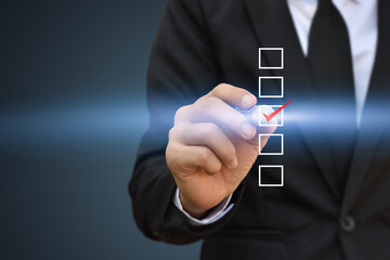 Businessman writing red check mark in a checkbox on blue background.