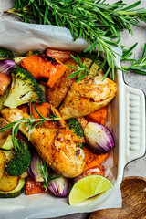 Roasted chicken legs with vegetables in the oven dish, top view. Baked chicken with sweet potato, zucchini and broccoli.