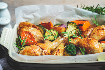 Roasted chicken legs with vegetables in the oven dish. Baked chicken with sweet potato, zucchini and broccoli.