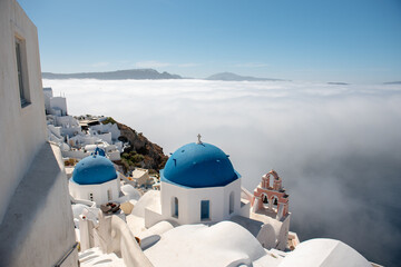 Famous blue domes in Oia village, Santorini island, Greece. Clouds covering caldera.
