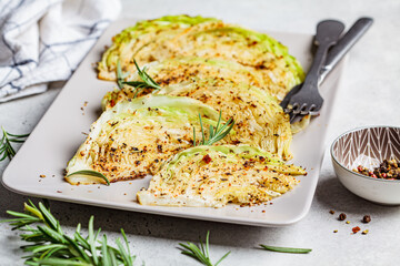 Baked cabbage steaks with spices on gray plate. Healthy vegan food concept.