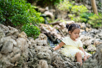 Cute little girl sitting on rock against streams