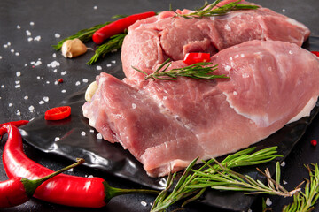 raw meat with rosemary, garlic  and red chili pepper, salt on a black