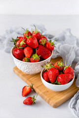 Heap of fresh strawberries in ceramic bowl on white table
