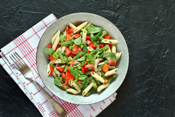 salad in a bowl of pasta, asparagus, bean pods, tomatoes, green peas, basil. top view, copy space