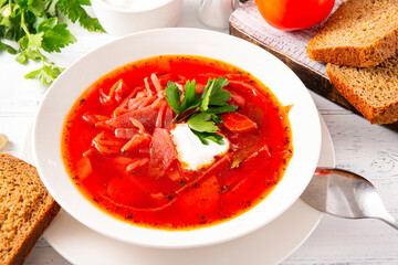 Ukrainian vegetable soup with bread, borscht with sour cream and parsley in a plate
