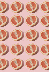 Grapefruit halves on pink background. Fruit pattern, flat lay