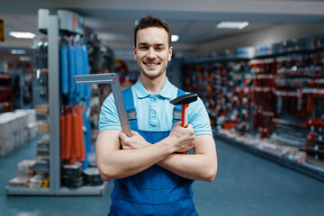 Worker holds hammer and corner in tool store