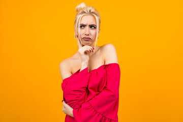sexy excited charming blonde girl in a red dress on a yellow studio background with copy space