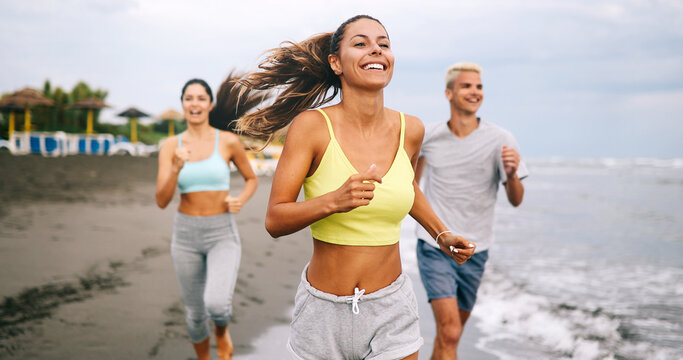 Group of athletes running on ocean front. Friends in sportswear training together outdoors.