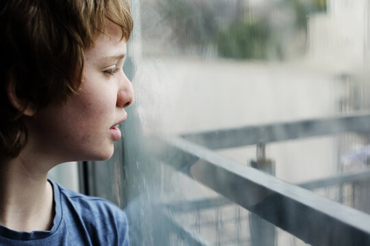 Cute 12 years old autistic boy looking through the window