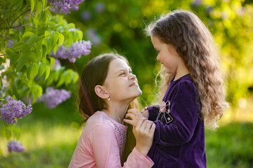 Obraz premium Two sisters play together outside the house in nature.