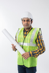 Confident young businessman holding blueprints on white background.