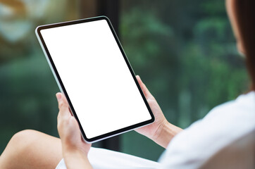 Mockup image of a woman holding black tablet pc with blank white desktop screen , green nature background