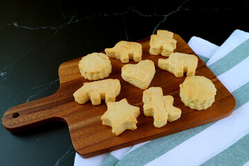 Homemade Delectable Cute Butter Cookies on Wooden Breadboard on Black Background