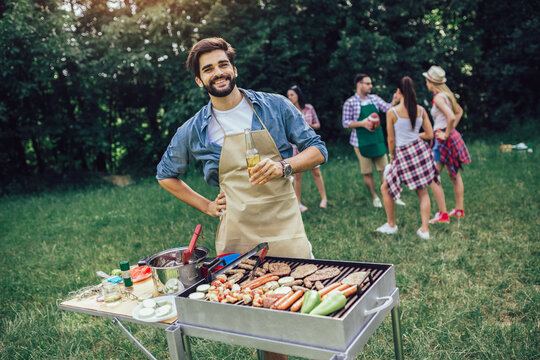 Young man preparing barbecue for friends outdoor