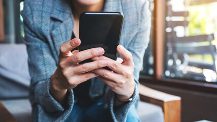 Closeup image of a woman holding and using mobile phone
