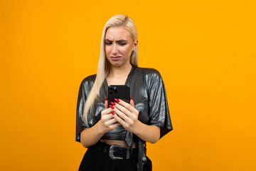 Fototapeta premium Caucasian girl with white hair is watching a site through a smartphone on a yellow background with copy space