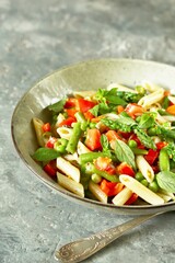 salad in a bowl of pasta, asparagus, bean pods, tomatoes, green peas, basil.