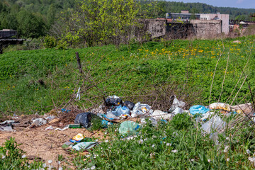 Garbage dump on a green meadow. Nearby plant.