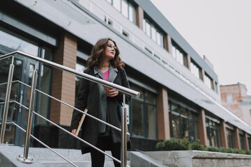 Fototapeta premium Beautiful curly lady on the stairs of modern building