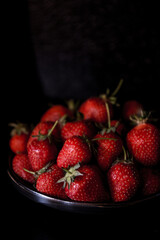 Fresh strawberries on dark moody background. Dark food photography.