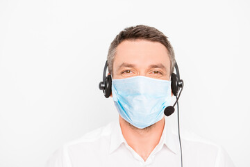 Portrait of mature man worker of call center assistance wear medical mask on face and headset with microphone help other people isolated on gray background, stop pandemic of corona virus concept