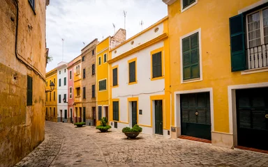 Abwaschbare Fototapete Enge Gasse urige schmale Gasse mit bunt bemalten Häusern in der Altstadt von Ciutadella mit Fluchtpunkt auf der linken Seite