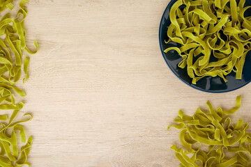 Raw green pasta with spinach on a dark blue plate, top view, copy space