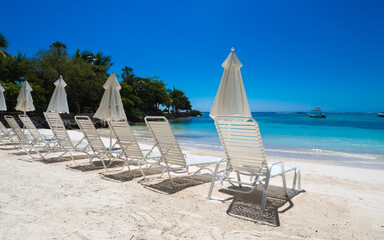 Naklejka premium a group of empty beach chairs inviting for a sunbath at a white beach in front of crystal clear water in the caribbean