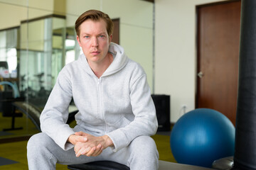 Fototapeta premium Young handsome man with hoodie sitting at the gym