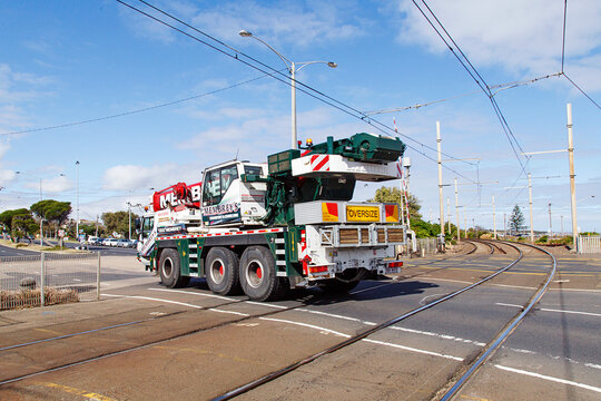 Melbourne, Australia: April 03, 2018: An oversized truck carrying a construction crane drives over the level crossing at Brighton Beach Railway Station which is located on the Sandringham line.