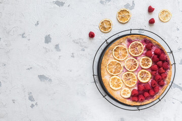 Cheese cake with raspberries and dried lemon slices on white background, top view with copy space