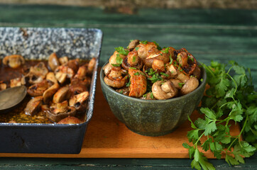 Mushrooms balsamico in a green bowl on a wooden board